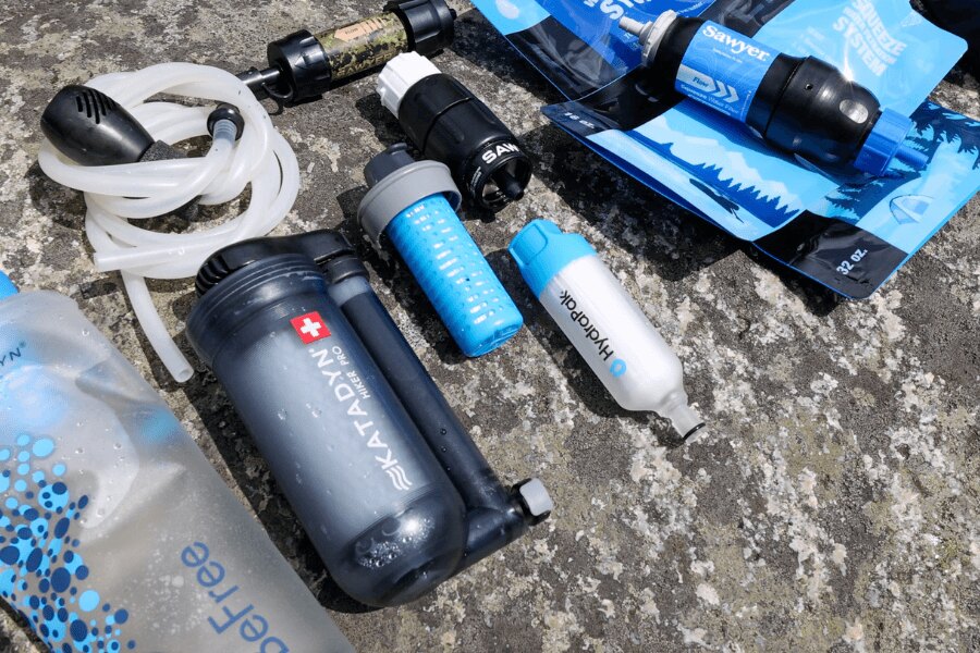 Sawyer, HydraPak és Katadyn különféle hordozható vízszűrő készletek egy kő alapon. Foto: Rigad