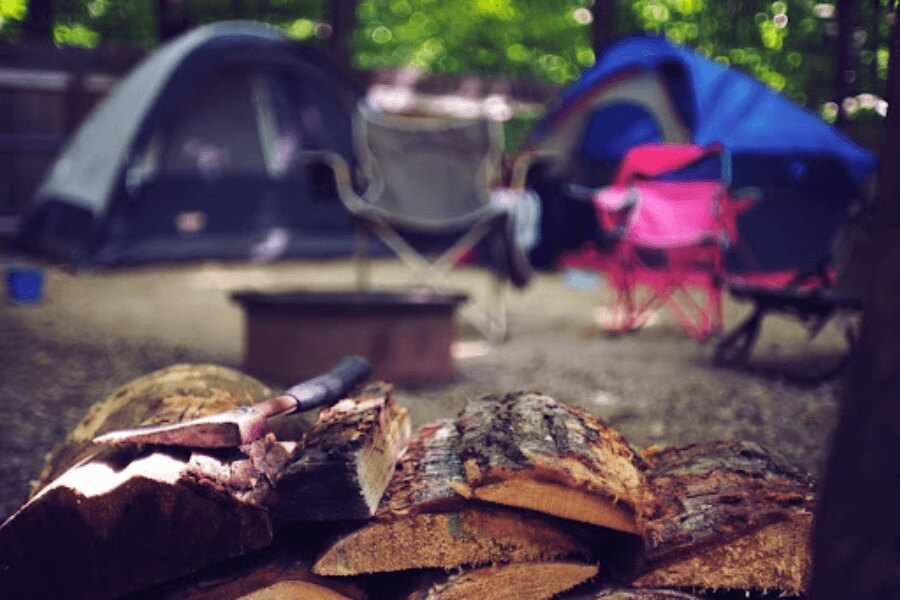 fejsze a fa mellett a kempingnél. Forrás: https://www.pexels.com/cs-cz/foto/drevo-krajina-dovolena-leto-2662831/