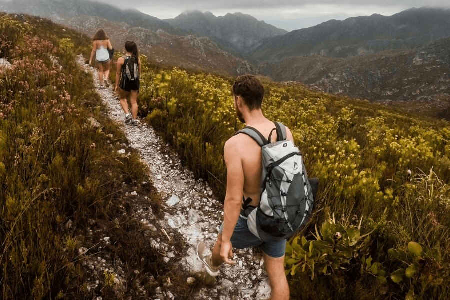 Férfi ing nélkül és két nő a hegyi úton. Forrás: https://www.pexels.com/cs-cz/foto/930685/