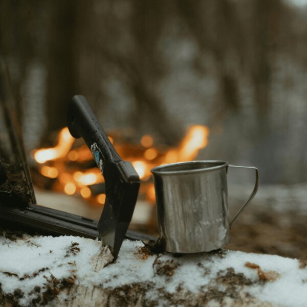 Bushcraft fejsze és bádogbögre az erdőben a tűz mellett. Forrás: https://www.pexels.com/cs-cz/foto/ryma-studeny-snih-priroda-6204650/