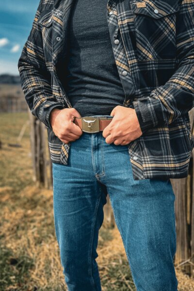 Egy férfi Treadstone Jeans<sup>®</sup> Helikon-Tex<sup>®</sup> nadrágban, kockás ingben, az övét fogja. Fotó: Rigad
