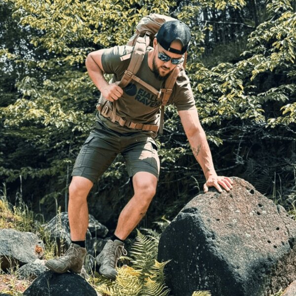 Egy férfi funkcionális outdoor ruházatban és hátizsákkal mászik egy sziklára az erdőben. Fotó: Rigad