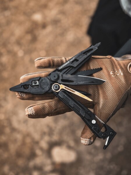 Multitool Leatherman MUT kinyitva, taktikai kesztyűben a tenyéren.