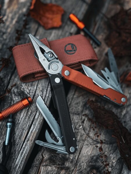 Leatherman Rebar multifunkciós szerszám szétnyitott fogókkal és kihúzott szerszámokkal egy fából készült felületen.