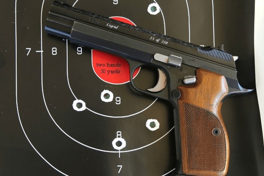A SIG P210 pisztoly a lőtéren lévő céltábla előtt van elhelyezve.
