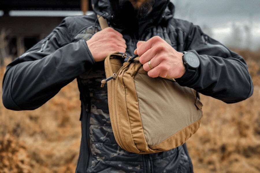 A sling bag főzsebének egy mozdulattal történő kinyitása a cipzárral, mielőtt a pisztolyt elővenné.