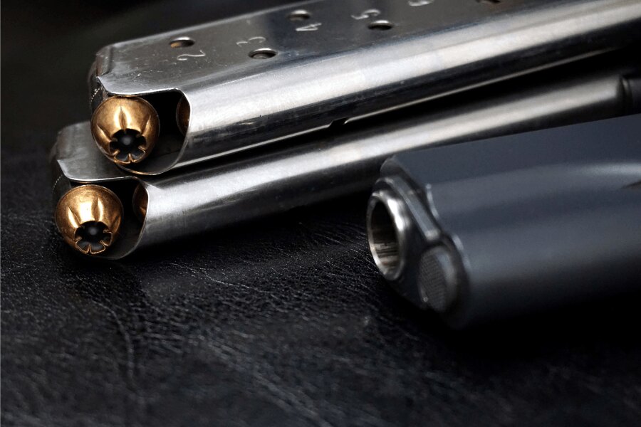 Részlet a M1911-es pisztoly tárairól, .45 ACP lőszerekkel és a háttérben a pisztoly egy része.