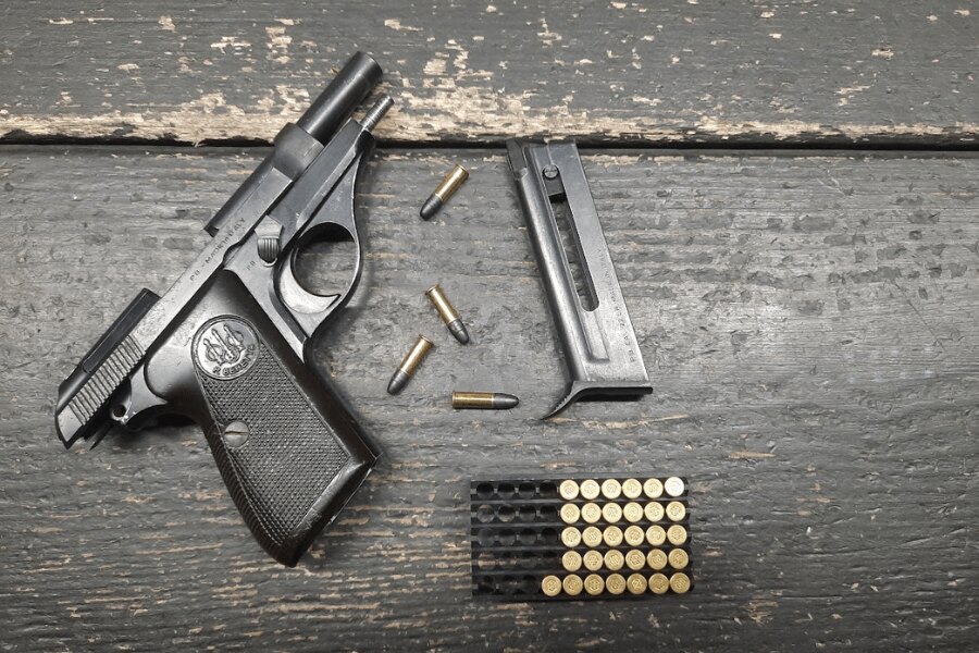 Beretta 71 pisztoly eltávolított tárral és .22 LR lőszerrel egy sötét faasztalon.