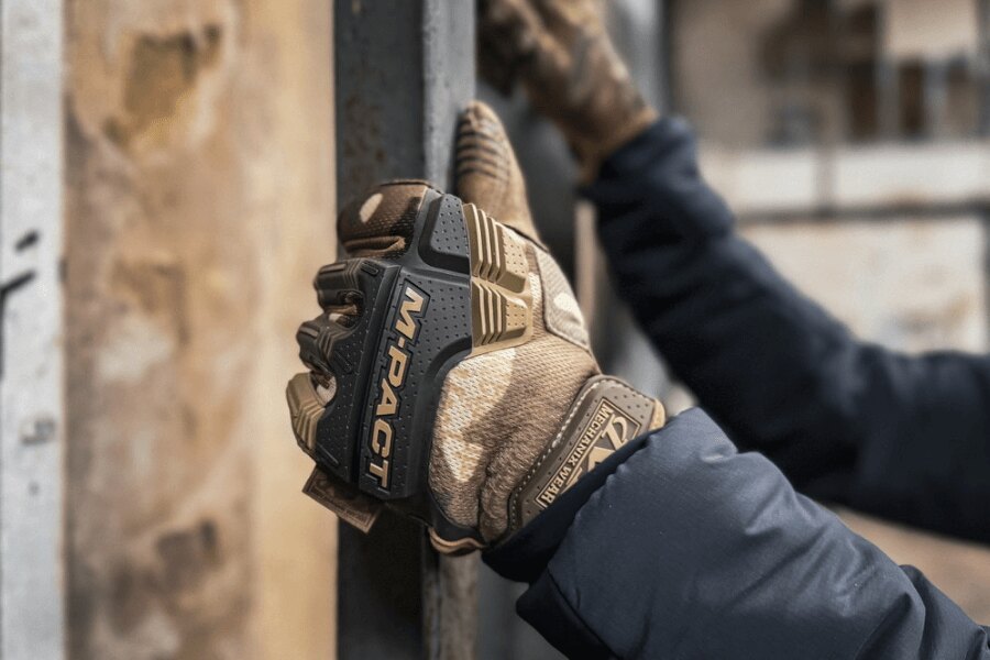 Mechanix M-Pact taktikai kesztyűs kezek fém szerkezet megfogásakor.